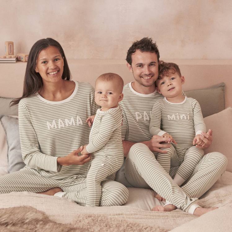 family wearing matching pajamas. Mom, dad, brother, and baby are all wearing light green and white striped long sleeve and pant pjs. The pajamas are ribbed and each features their title printed on the chest (mama, papa, mini)
